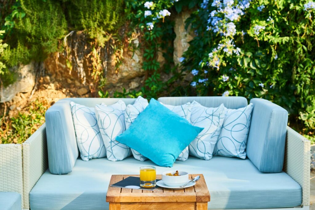 Inviting outdoor patio with a cozy sofa, cushions, and a refreshing drink on a wooden table.